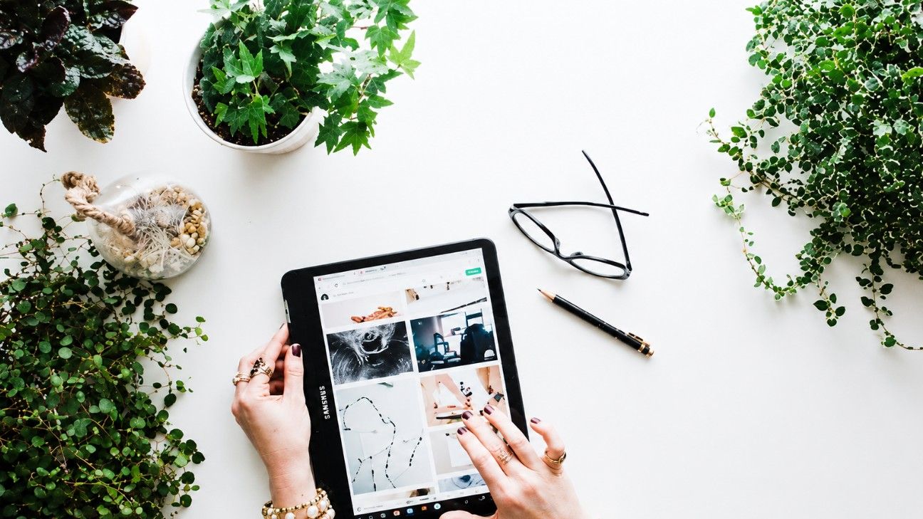 Pessoa a utilizar um tablet numa secretária rodeada de plantas