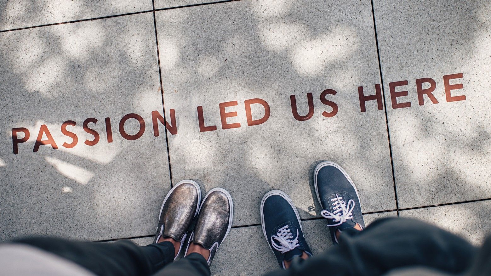 Duas pessoas junto a uma parede com a frase “Passion Led Us Here”